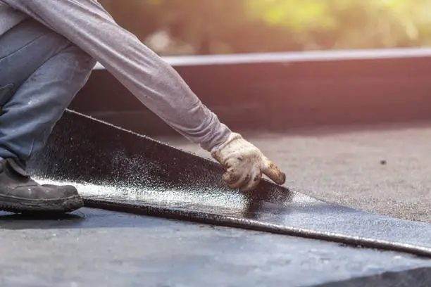 Hand applying Elastrocryl Fiber rubber waterproofing coating to a roof